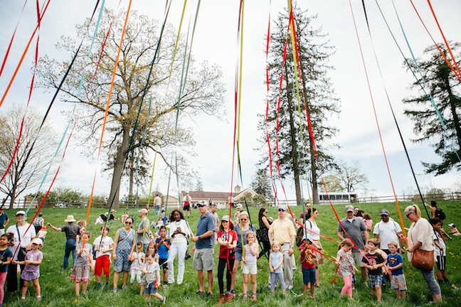 Guests and children raising May Pole in pasture at 2017 Sheep Shearing Fest